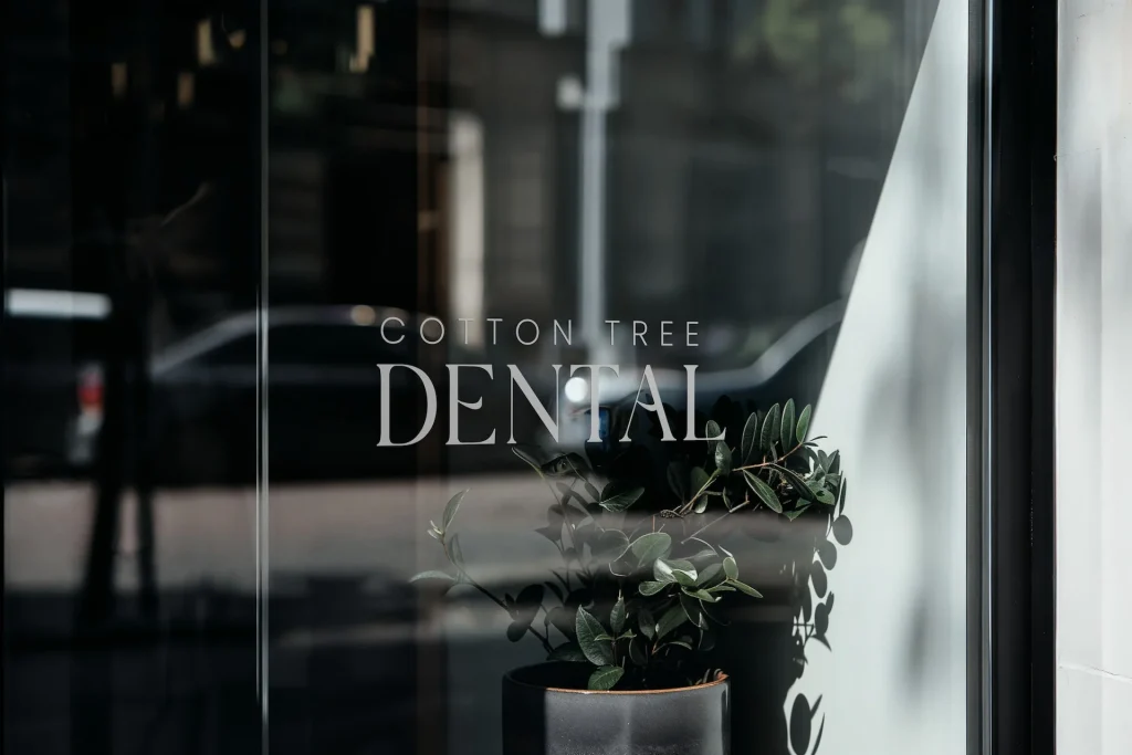 Cotton Tree Dental logo displayed on the clinic's glass entrance with a potted plant.