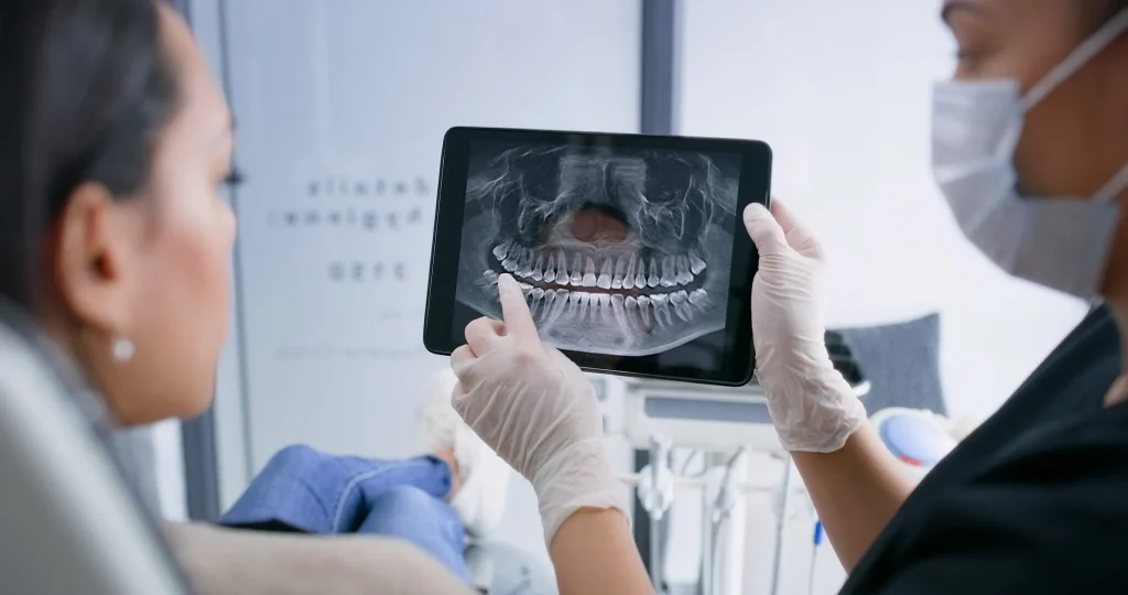 Dentist reviewing a patient's digital dental X-ray on a tablet during a consultation in a modern dental clinic, supporting accurate diagnosis and treatment planning.