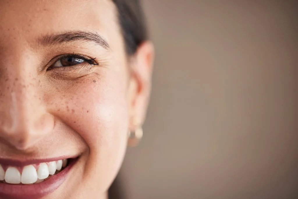 Close-up of a smiling woman with healthy white teeth and radiant skin, highlighting a confident smile and excellent oral health.