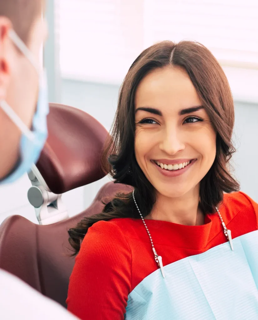 Smiling woman consulting with a dentist in a modern dental clinic after gum contouring treatment, showcasing a healthy, balanced smile and improved gum aesthetics.